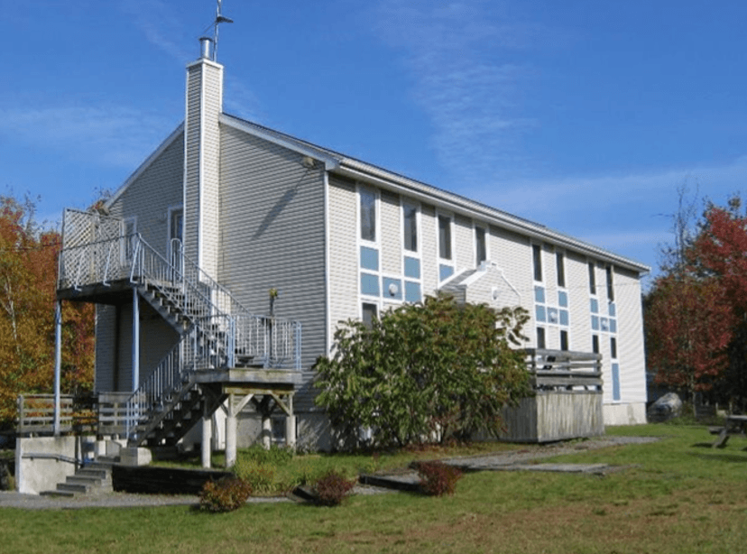 An outside shot of the field station, a two-story white building with rectangular windows and a pointed roof.